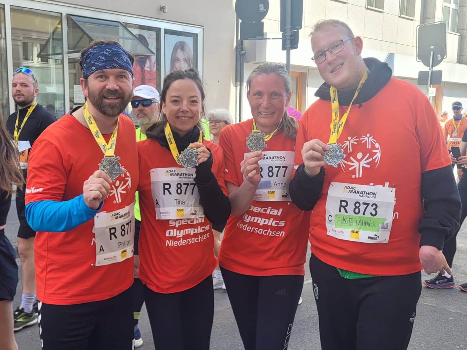 4 Personen, in Laufbekleidung, die Plaketen zeigen