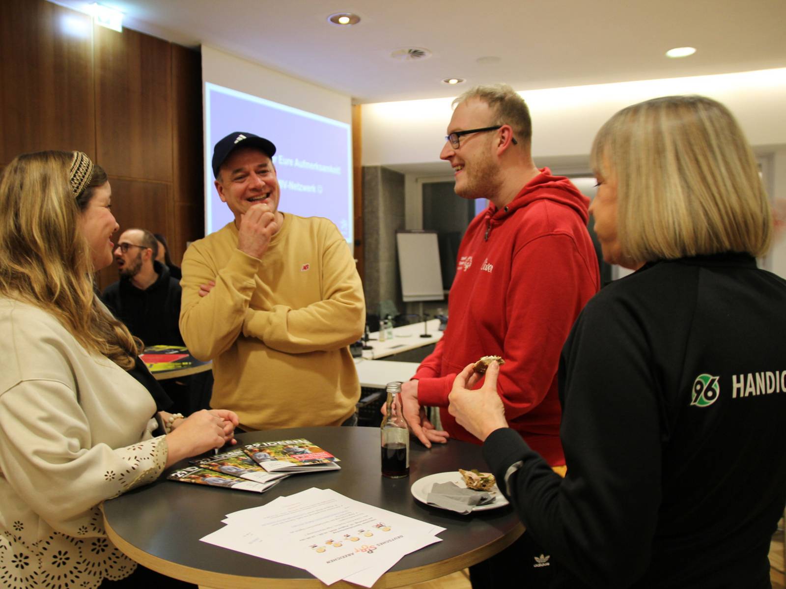 Vier Personen an einem Stehtisch im Gespräch