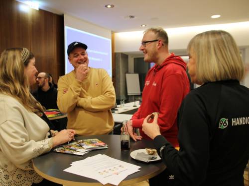 Vier Personen an einem Stehtisch im Gespräch