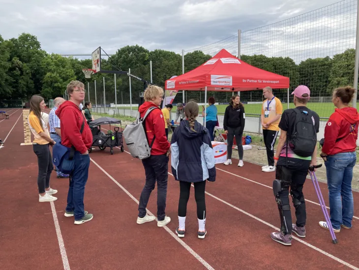 Ein Stand auf einem Sportplatz, drumherum Menschen