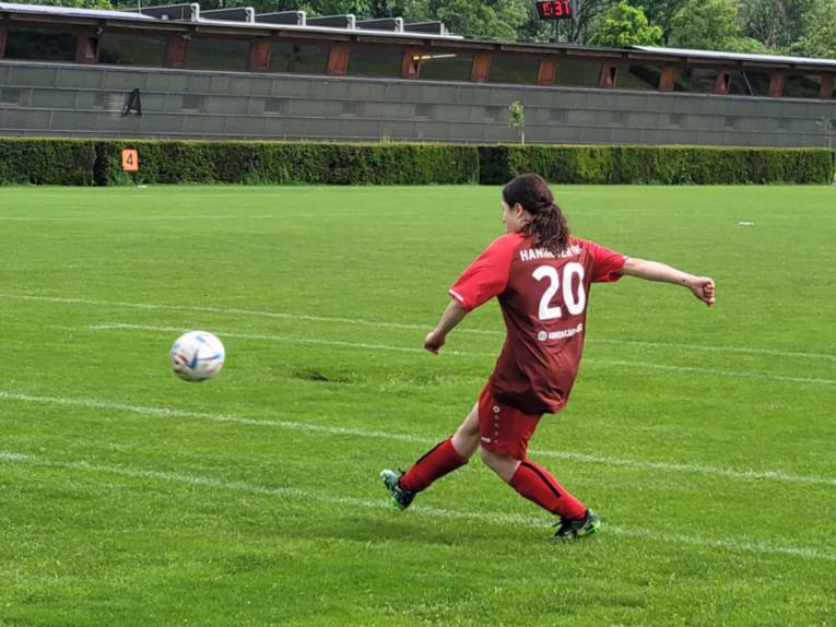 Ein fliegender Ball und eine Person, im Begriff den Ball mit dem Fuß anzunehmen oder die Person hat den Ball gerade abgeschlagen