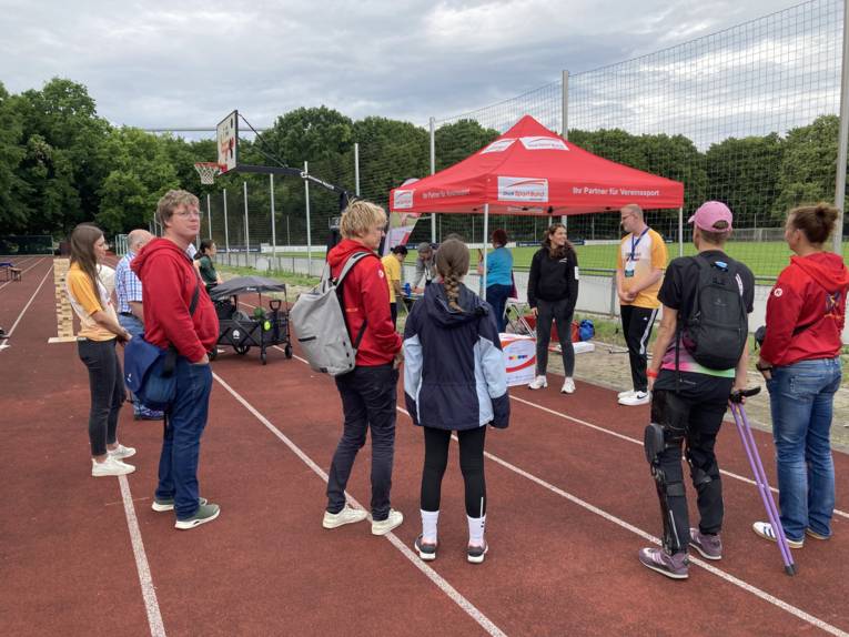 Ein Stand auf einem Sportplatz, drumherum Menschen